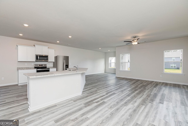 kitchen with a kitchen island with sink, light hardwood / wood-style floors, white cabinets, and appliances with stainless steel finishes