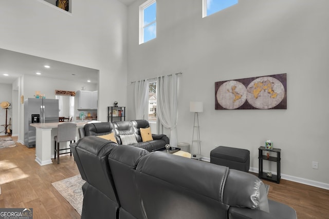 living room with light hardwood / wood-style flooring, a high ceiling, and plenty of natural light