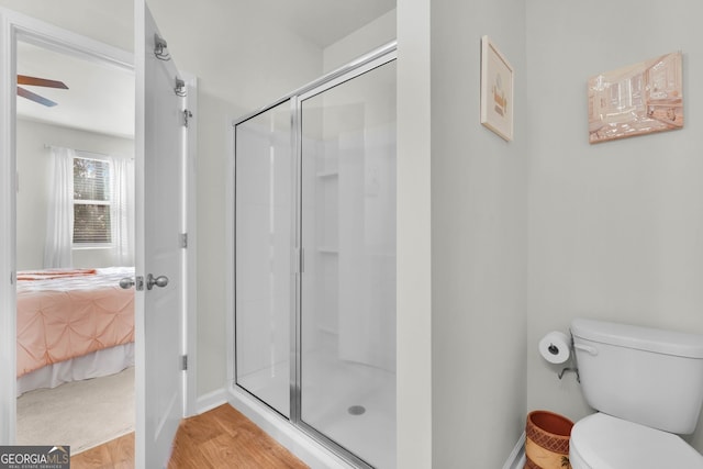 bathroom with a shower with door, hardwood / wood-style floors, and toilet