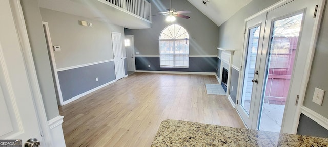 unfurnished living room featuring light hardwood / wood-style flooring, ceiling fan, and vaulted ceiling