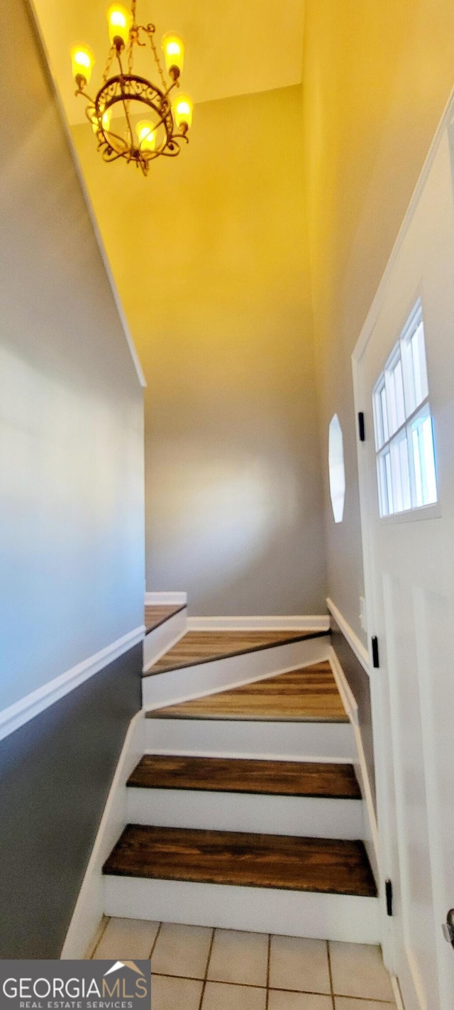 stairs with tile patterned flooring and a notable chandelier