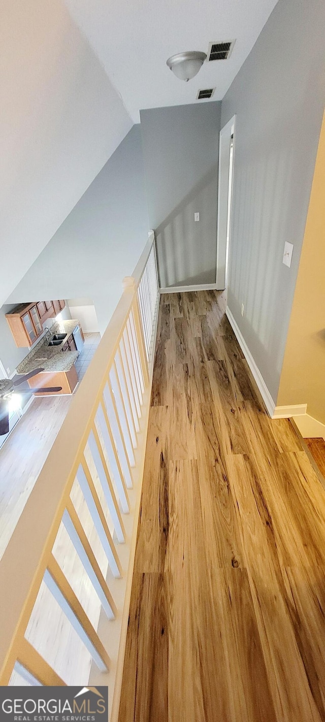 stairs with wood-type flooring and vaulted ceiling