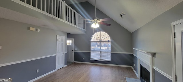 unfurnished living room with high vaulted ceiling, ceiling fan, and light wood-type flooring