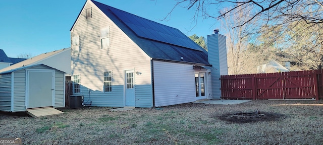 back of house with a yard, central air condition unit, and a storage unit