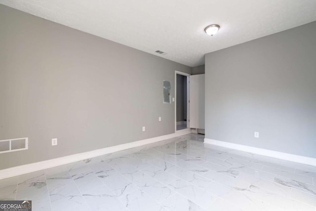 unfurnished room featuring electric panel and a textured ceiling