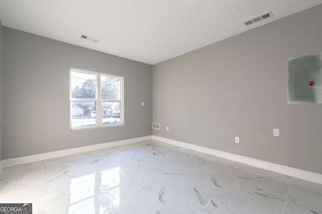 empty room with electric panel and a textured ceiling