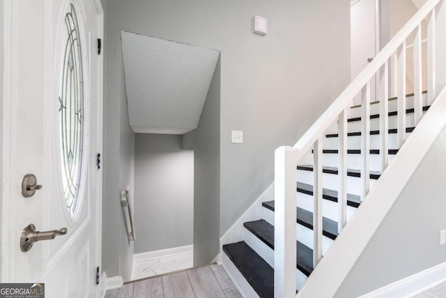 staircase featuring wood-type flooring and a textured ceiling