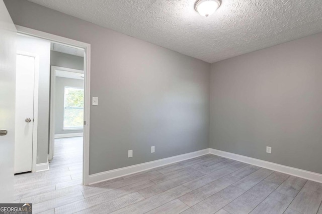 spare room with light hardwood / wood-style flooring and a textured ceiling