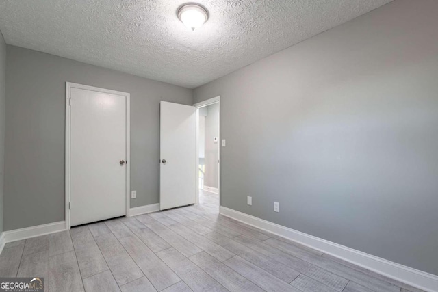 unfurnished bedroom featuring a textured ceiling and light hardwood / wood-style floors