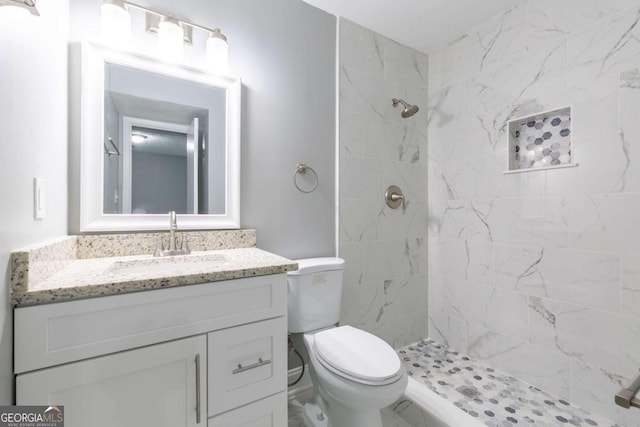 bathroom featuring tiled shower, vanity, and toilet