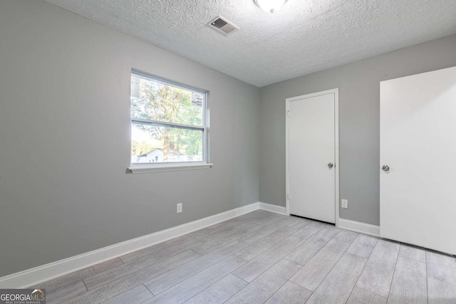 empty room featuring light hardwood / wood-style floors and a textured ceiling