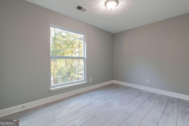 spare room with a textured ceiling and light wood-type flooring