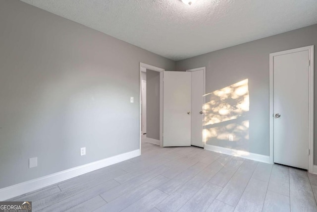 unfurnished bedroom with a textured ceiling and light wood-type flooring