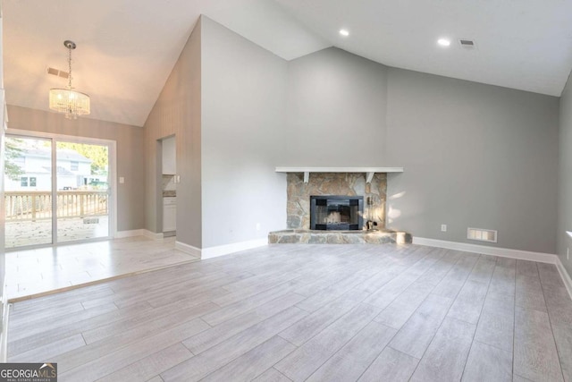 unfurnished living room with a fireplace, a chandelier, high vaulted ceiling, and light hardwood / wood-style flooring