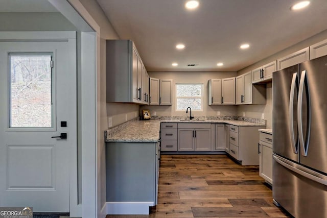 kitchen featuring light stone counters, sink, dark hardwood / wood-style floors, and stainless steel refrigerator