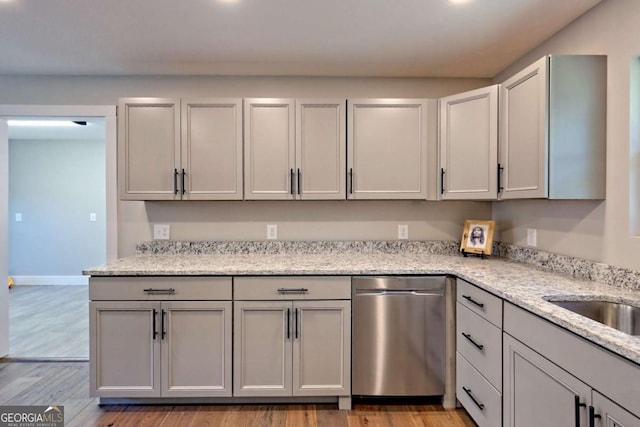 kitchen featuring gray cabinetry, light hardwood / wood-style flooring, light stone countertops, and dishwasher