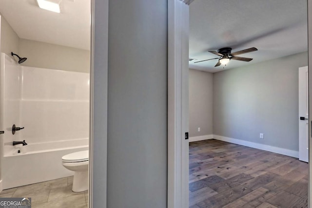 bathroom featuring hardwood / wood-style flooring, shower / bathtub combination, toilet, and ceiling fan