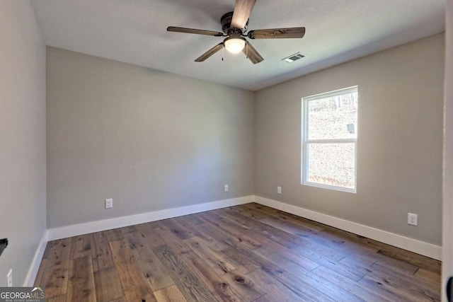 spare room with dark hardwood / wood-style flooring and ceiling fan