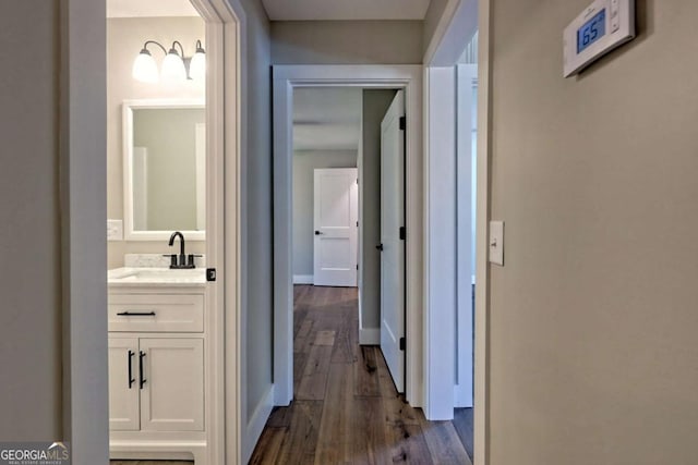 corridor with dark hardwood / wood-style flooring and sink