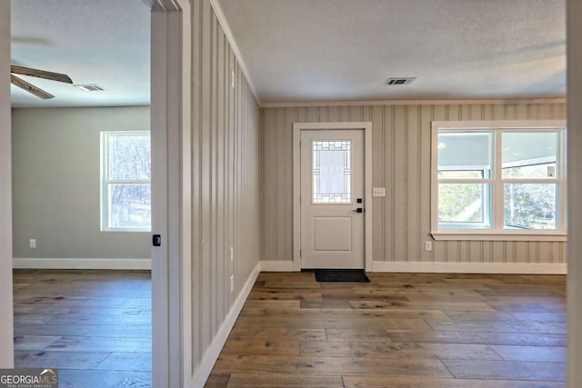 entrance foyer featuring ceiling fan, plenty of natural light, dark hardwood / wood-style flooring, and ornamental molding