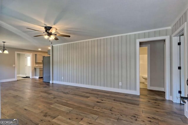 unfurnished living room with ceiling fan with notable chandelier, ornamental molding, and dark hardwood / wood-style floors