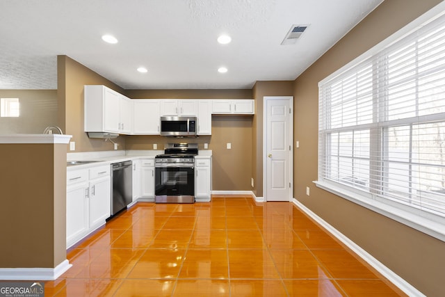 kitchen with light tile patterned floors, a textured ceiling, stainless steel appliances, and white cabinets