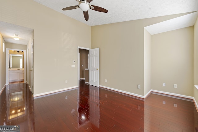 spare room with ceiling fan, vaulted ceiling, a textured ceiling, and dark hardwood / wood-style flooring