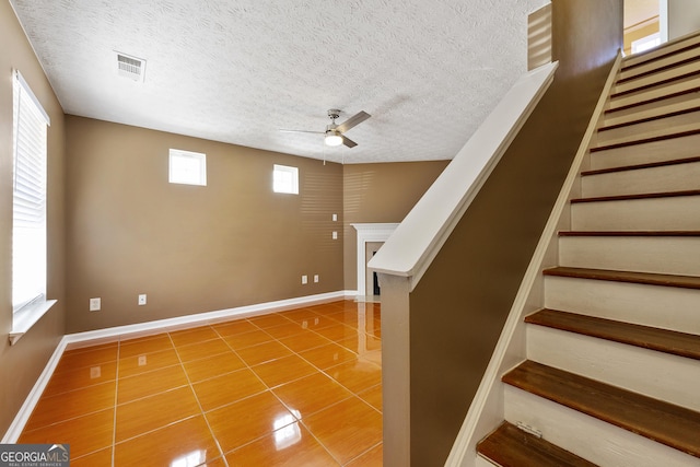 interior space with tile patterned flooring, a textured ceiling, and ceiling fan