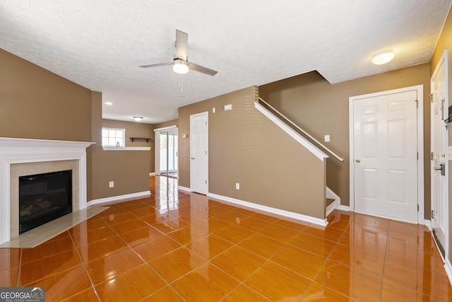 unfurnished living room featuring ceiling fan, tile patterned floors, and a textured ceiling