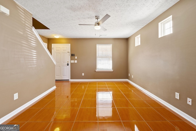 foyer entrance with tile patterned flooring, a textured ceiling, and ceiling fan