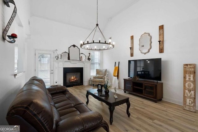 living room with a tiled fireplace, hardwood / wood-style flooring, high vaulted ceiling, and an inviting chandelier