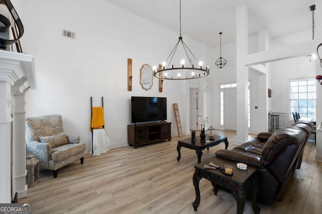 living room featuring a chandelier, decorative columns, light hardwood / wood-style flooring, and a high ceiling