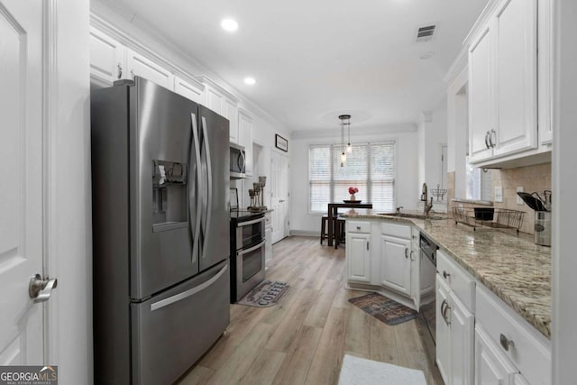 kitchen featuring sink, crown molding, stainless steel appliances, white cabinets, and decorative light fixtures