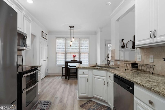 kitchen featuring sink, crown molding, appliances with stainless steel finishes, white cabinets, and decorative light fixtures