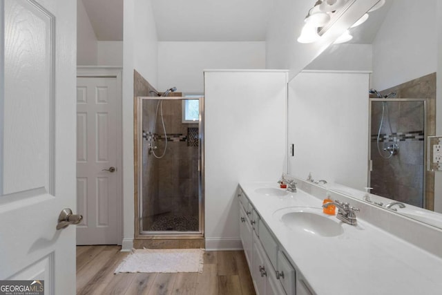 bathroom featuring wood-type flooring, a shower with shower door, and vanity