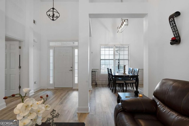 foyer entrance with a towering ceiling, a chandelier, and light wood-type flooring