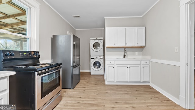 kitchen with appliances with stainless steel finishes, sink, white cabinets, ornamental molding, and stacked washer and clothes dryer