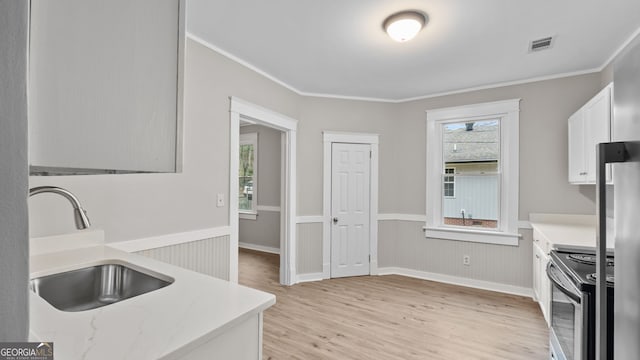 kitchen with white cabinetry, sink, crown molding, light wood-type flooring, and electric stove