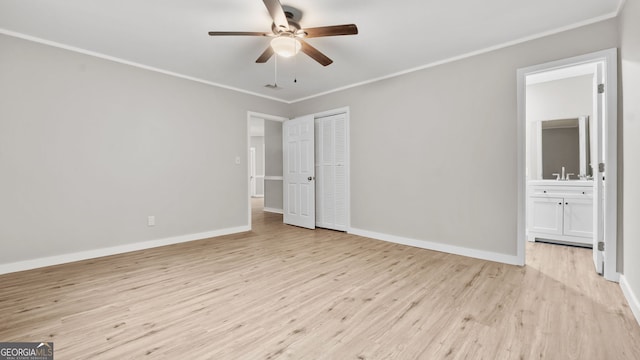 unfurnished bedroom with a closet, ornamental molding, ensuite bathroom, and light hardwood / wood-style flooring