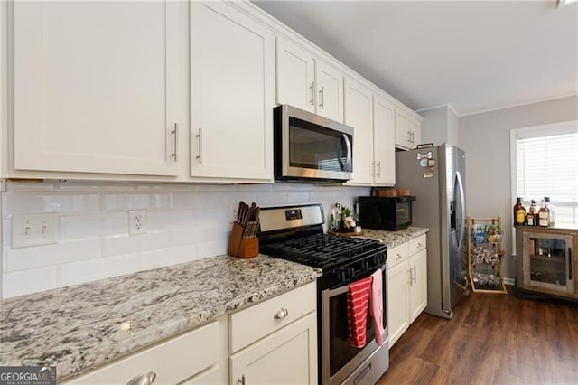 kitchen featuring white cabinetry, backsplash, stainless steel appliances, dark hardwood / wood-style floors, and light stone counters