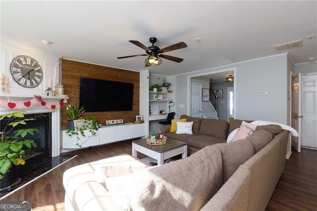 living room featuring crown molding, ceiling fan, a premium fireplace, and dark hardwood / wood-style flooring