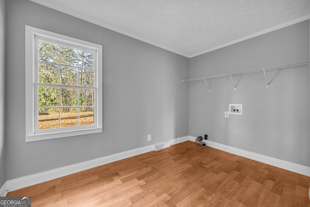 laundry area featuring ornamental molding, hookup for a washing machine, hardwood / wood-style floors, and a textured ceiling