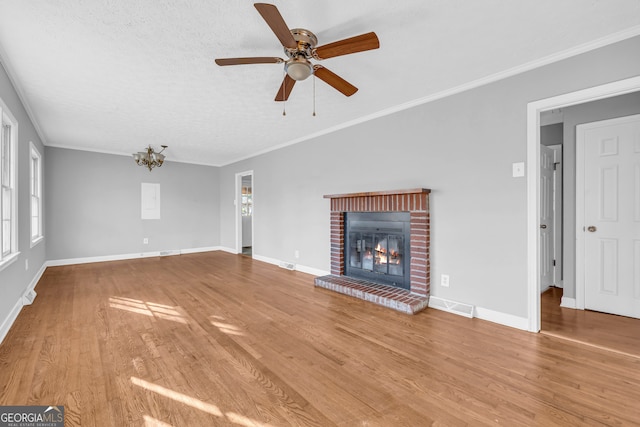 unfurnished living room featuring a textured ceiling, light wood-type flooring, ornamental molding, ceiling fan, and a fireplace