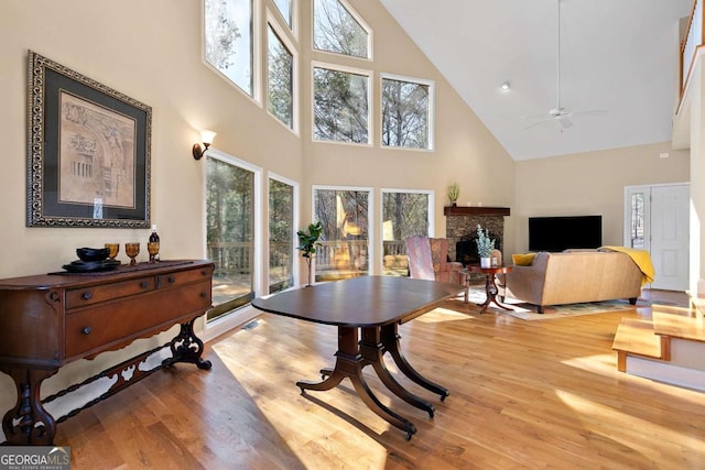 living room with high vaulted ceiling, ceiling fan, and light hardwood / wood-style flooring