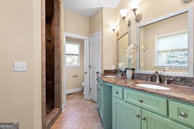 bathroom featuring tiled shower, vanity, toilet, and tile patterned flooring