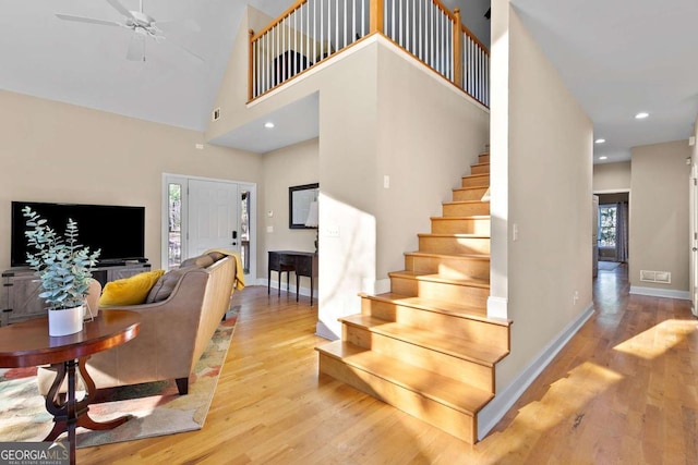 staircase with hardwood / wood-style flooring, ceiling fan, and a towering ceiling