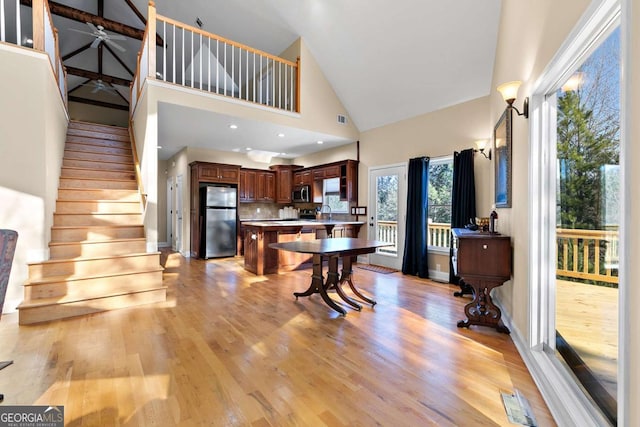 kitchen with sink, light hardwood / wood-style flooring, high vaulted ceiling, and appliances with stainless steel finishes