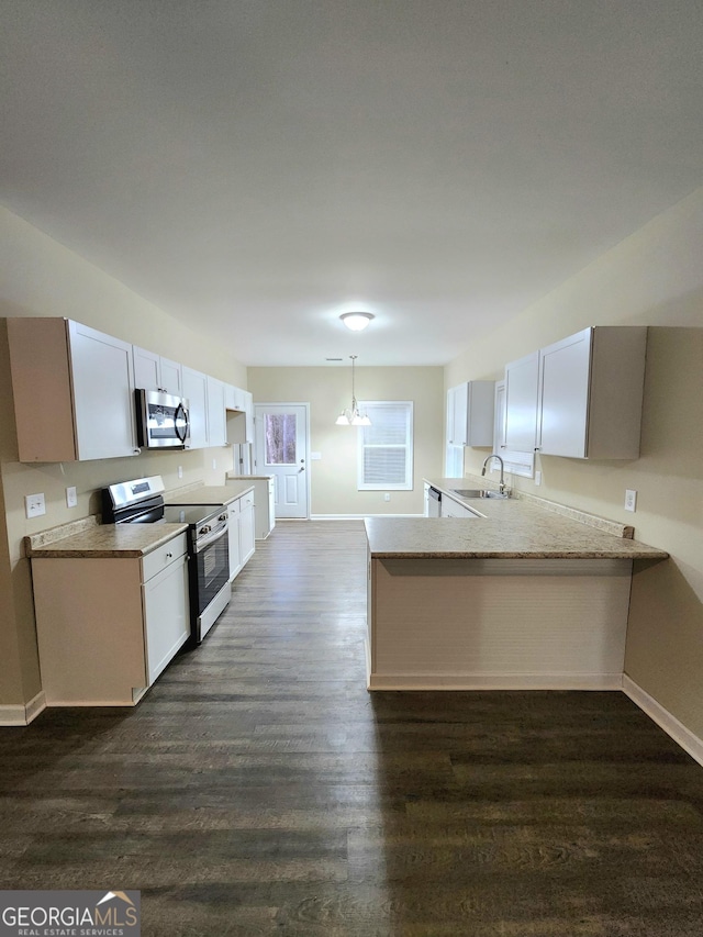 kitchen with sink, white cabinetry, stainless steel appliances, dark hardwood / wood-style flooring, and kitchen peninsula