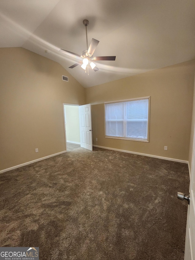 unfurnished bedroom with dark carpet, ceiling fan, and vaulted ceiling