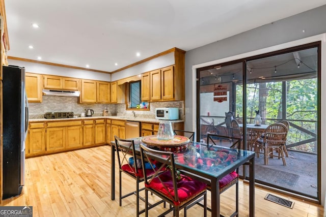 kitchen with ornamental molding, appliances with stainless steel finishes, light wood-type flooring, and decorative backsplash